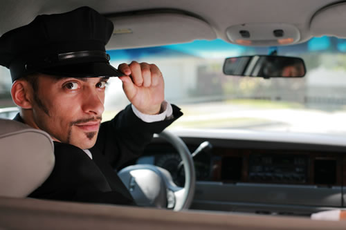 A professional chauffeur in uniform behind the wheel.