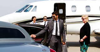 Passengers boarding a private vehicle next to a jet on the tarmac.